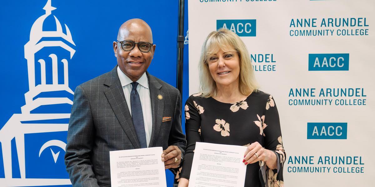 Presidents of Morgan State University and AACC hold up signed articulation agreements.