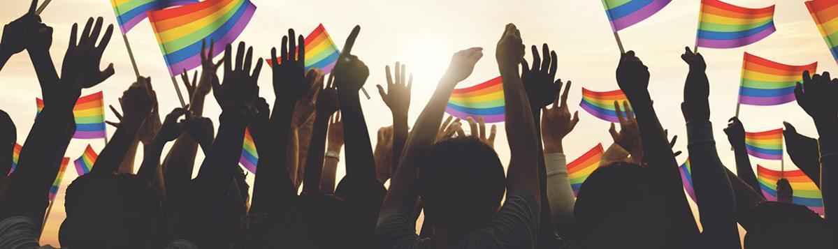 Crowd of hands waiving rainbow flags.