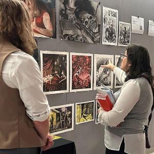 Person looking at a student's art display in a hallway with other displays.