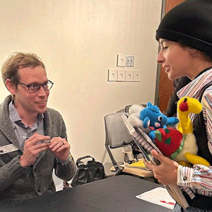 Student at display table with a representative from a college.