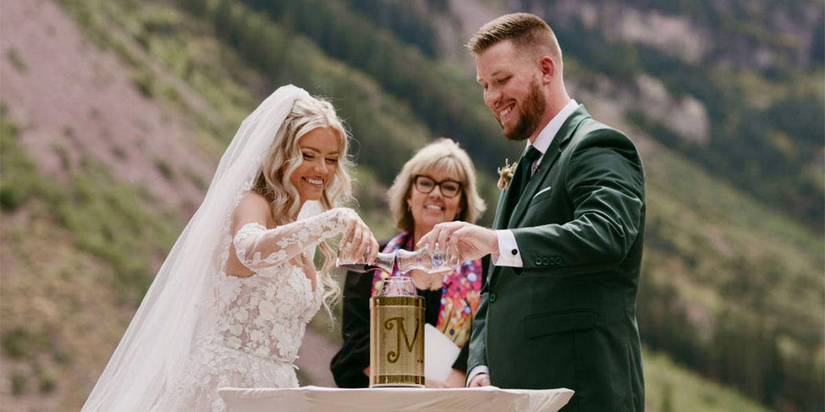 Audra Butler, standing in the middle, officiates a wedding. Mountains appear in the background.