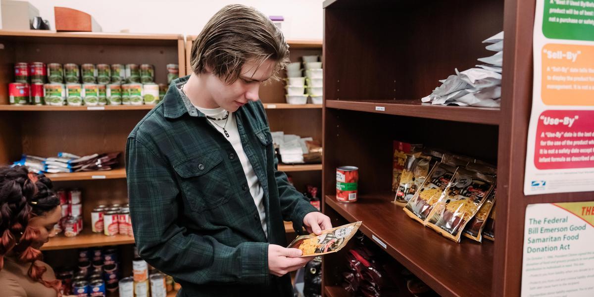 A student examines a package of food in AACC's food pantry.