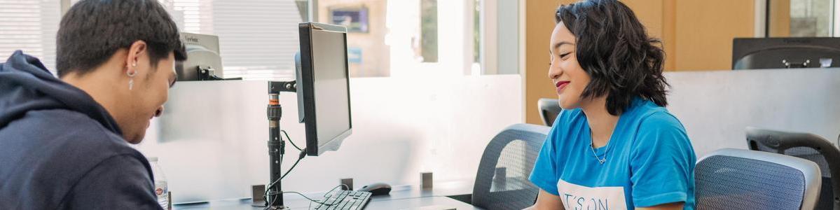 Students talking to one another at a desk.