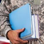 Military man in uniform with books.