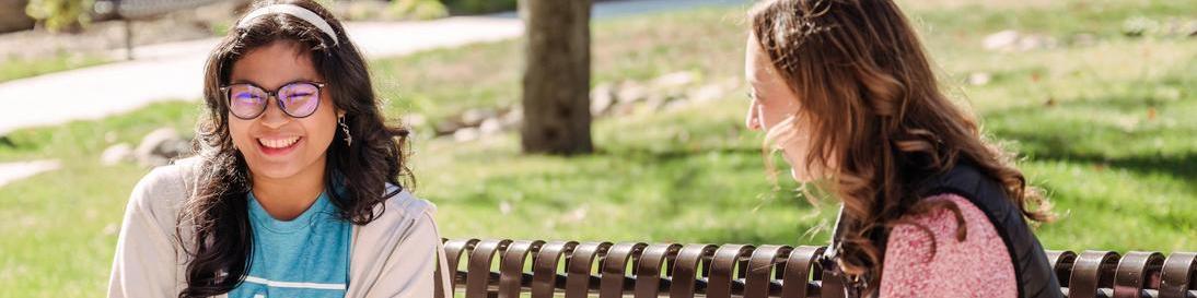 Two AACC students talking to each other on bench.