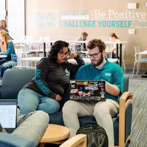 Students looking at computers together in a study space.