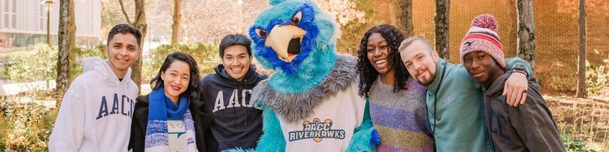 Students laughing and posing with AACC mascot, Swoop.